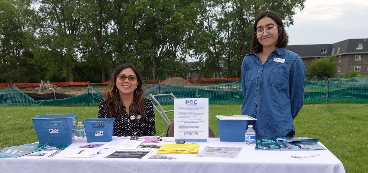 smiling volunteers outside with a table POC materials in front of them
