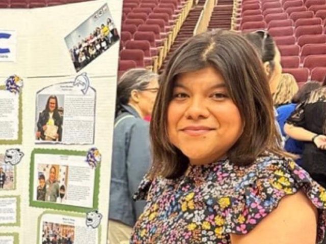 smiling woman looking into the camera with at poster board next to her