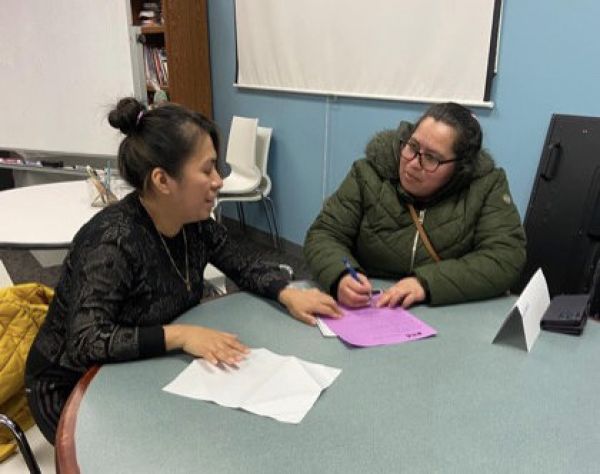 Two women sitting at a round table reviewing pages